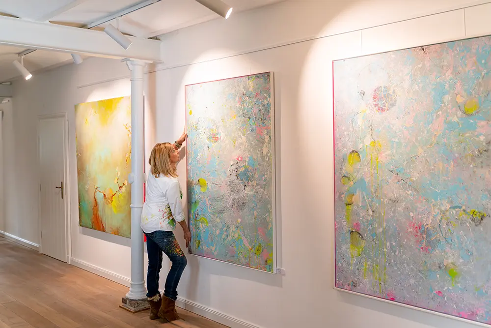 atelier werke und werte Birgit Dierker hängt ein Bild auf im Atelier